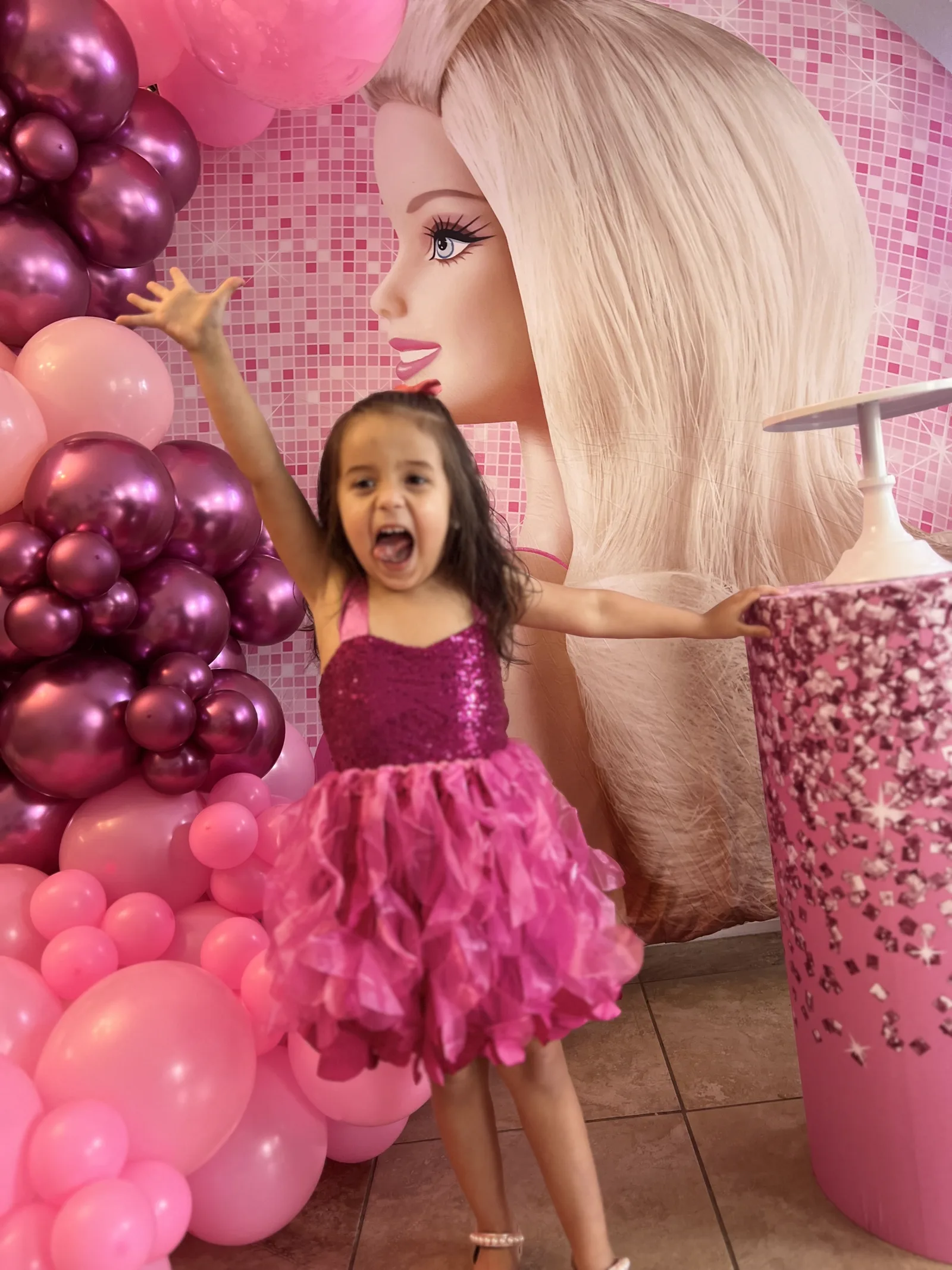 Child celebrating in front of a pink themed party backdrop