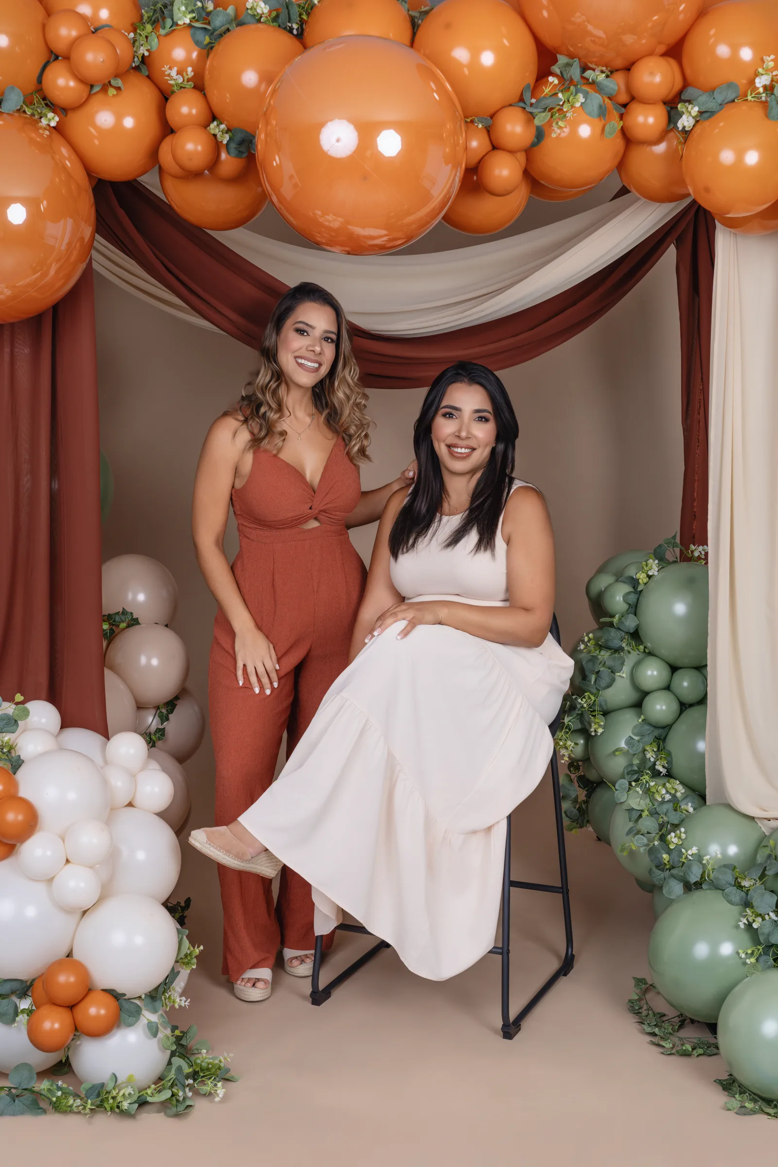 Guests seated in front of a warm-toned organic balloon garland